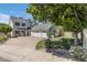 Beautiful two-story white home featuring an attached three-car garage, luscious lawn, and mature trees under a clear blue sky at 7348 N 9Th Pl, Phoenix, AZ 85020
