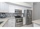 Kitchen features stainless appliances, white cabinets, granite countertops, tile backsplash, and wood-look tile floors at 7949 W Wescott Dr, Glendale, AZ 85308
