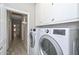 Functional laundry room with a front-loading washer and dryer, white cabinets, and hallway access at 7949 W Wescott Dr, Glendale, AZ 85308