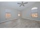 Spacious primary bedroom with wood-look tile flooring, ceiling fan, and three windows at 7949 W Wescott Dr, Glendale, AZ 85308