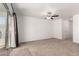 Bright living room features plush carpet, ceiling fan and a sliding glass door leading to the outside at 8577 S 253Rd Dr, Buckeye, AZ 85326