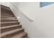 Carpeted stairs with white railings and subtle inset lighting for added safety and aesthetic appeal at 8577 S 253Rd Dr, Buckeye, AZ 85326