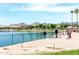 Picturesque lake view with a sandy beach and people strolling, surrounded by palm trees and mountains at 8683 S 165Th Ave, Goodyear, AZ 85338