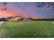 Vast backyard with green lawn and patio, set against a vibrant sunset sky at 9005 W Villa Chula St, Peoria, AZ 85383
