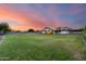 Huge backyard featuring green lawn and views of the home and covered patio under a beautiful sunset sky at 9005 W Villa Chula St, Peoria, AZ 85383