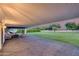 Expansive covered backyard patio with brick pavers, seating, hammock and view of large green lawn at 9005 W Villa Chula St, Peoria, AZ 85383