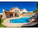 Backyard with a sparkling blue pool, rock waterfall feature, shaded patio, and lush landscaping for relaxation and enjoyment at 10723 N 118Th Way, Scottsdale, AZ 85259