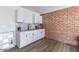 A charming kitchenette featuring white cabinets, granite countertops, and modern fixtures set against an exposed brick wall at 1322 W Flower St, Phoenix, AZ 85013