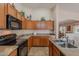 A kitchen with wood cabinets, a black microwave and stove, and stainless steel sink at 1520 N Milly Pl, Casa Grande, AZ 85122