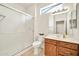 Cozy bathroom showcasing a glass door shower, tiled floors, and a wooden vanity with a mirror and lighting at 15534 W Big Sky Dr, Surprise, AZ 85374