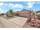 Single-Gathering home with desert landscaping, a two-car garage, flowering cactus, and a well-manicured lawn at 15534 W Big Sky Dr, Surprise, AZ 85374