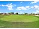 Picturesque golf course with vibrant green grass, a blue flag marking the hole, and homes in the distance at 15534 W Big Sky Dr, Surprise, AZ 85374