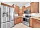 Modern kitchen with stainless steel appliances, natural cabinets, and tile floor at 15534 W Big Sky Dr, Surprise, AZ 85374