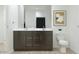 Modern bathroom featuring a double sink vanity with dark cabinets, chrome hardware, toilet and framed wall art at 17348 W Smoketree Dr, Surprise, AZ 85387
