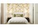 Elegant bedroom showcasing a leaf-patterned wallpaper, complemented by stylish lamps and soft bedding at 17349 W Smoketree Dr, Surprise, AZ 85387