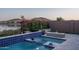Inviting pool and spa area with modern fire feature, framed by picturesque landscaping and lake backdrop at 18135 W Hope Dr, Goodyear, AZ 85338