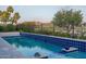 Serene pool area featuring lush landscaping and a peaceful lake view, creating a relaxing atmosphere at 18135 W Hope Dr, Goodyear, AZ 85338