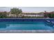Beautiful pool with a tiled border and a tranquil lake view, enhanced by lush landscaping at 18135 W Hope Dr, Goodyear, AZ 85338