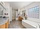 Bright bathroom with double sinks, soaking tub, glass block window, and walk-in glass block shower at 19242 W Pasadena Ave, Litchfield Park, AZ 85340