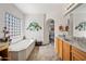 Relaxing bathroom with soaking tub, tiled floors, vanity with sink, and decorative art at 19242 W Pasadena Ave, Litchfield Park, AZ 85340