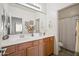 Bathroom vanity featuring wood cabinets, double sinks, a large mirror, and a nearby toilet and shower at 19242 W Pasadena Ave, Litchfield Park, AZ 85340