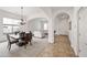 An elegant dining area featuring modern chandelier lighting, neutral colors, and an arched doorway to the living area at 19242 W Pasadena Ave, Litchfield Park, AZ 85340