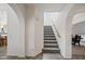 Elegant staircase with carpeted steps, white walls, and arched doorways at 19242 W Pasadena Ave, Litchfield Park, AZ 85340
