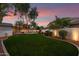 Spacious backyard with green lawn, landscape lighting, manicured trees and shrubs, and a block fence at 20412 W Thayer St, Buckeye, AZ 85396