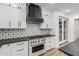 Stylish kitchen featuring white cabinets, black countertops, a patterned backsplash, and stainless steel appliances at 20412 W Thayer St, Buckeye, AZ 85396