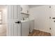 Clean laundry room with white appliances, overhead storage, and modern tile flooring at 20412 W Thayer St, Buckeye, AZ 85396