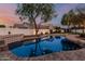 Twilight scene of a backyard swimming pool surrounded by lush landscaping and ambient lighting at 20412 W Thayer St, Buckeye, AZ 85396