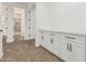 A view of a walk-in closet featuring custom cabinets and countertop with a doorway to an ensuite bathroom at 20412 W Thayer St, Buckeye, AZ 85396