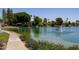 Waterfront sidewalk with landscaping and a pond with a fountain in a lush, green community at 2309 W Naranja Ave, Mesa, AZ 85202