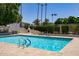 A community pool is surrounded by mature landscaping with tiled pool decking and a built-in fireplace at 2309 W Naranja Ave, Mesa, AZ 85202