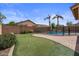 Outdoor oasis with putting green, pool with waterfall feature, brick patio, desert plants, and block fencing at 4323 E Dublin St, Gilbert, AZ 85295