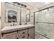 Bathroom featuring double sinks, framed vanity mirror, and a glass-enclosed shower with marble at 5526 W Ellis Dr, Laveen, AZ 85339