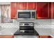 Stainless steel microwave and electric range on a countertop with mosaic tile backsplash and wood cabinets at 681 W Racine Loop, Casa Grande, AZ 85122