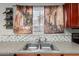Kitchen sink area with stainless steel sink, mosaic tile backsplash, and charming curtain with street scene at 681 W Racine Loop, Casa Grande, AZ 85122