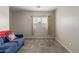 Cozy living room with a blue sofa, American flag pillow, carpet flooring, and natural light from the window at 681 W Racine Loop, Casa Grande, AZ 85122