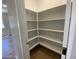 Walk-in pantry featuring multiple tiers of white shelving, and light brown wood-look tile flooring at 7243 E Cattle Call St, San Tan Valley, AZ 85143