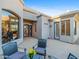 Inviting front entrance features a decorative metal door, arched window, and outdoor seating on a patterned stone patio at 9878 N 79Th Pl, Scottsdale, AZ 85258