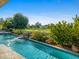 A clear swimming pool featuring a rock waterfall, set against a golf course backdrop at 9878 N 79Th Pl, Scottsdale, AZ 85258