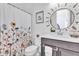 Bright bathroom with floral shower curtain, patterned floor tiles, and a decorative sun mirror at 10006 E Rotation Dr, Mesa, AZ 85212