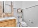 Stylish half-bathroom featuring a wooden vanity, framed mirror, decorative shelf, and white toilet at 10006 E Rotation Dr, Mesa, AZ 85212