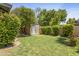Well-maintained backyard with mature trees, lush lawn, and a storage shed at 12639 N 47Th Ave, Glendale, AZ 85304