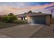 Single story home featuring mature landscaping, brick accents and a two car garage at dusk at 12639 N 47Th Ave, Glendale, AZ 85304