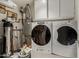 Functional laundry room featuring a modern washer and dryer set, along with a water heater and essential cleaning supplies at 12837 N 68Th St, Scottsdale, AZ 85254
