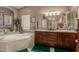The main bathroom features double sinks, a large mirror, a separate tub, and warm earth tone colors at 12837 N 68Th St, Scottsdale, AZ 85254