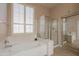 Bright bathroom featuring a soaking tub, a glass shower enclosure, and plantation shutters at 18226 W Stinson Dr, Surprise, AZ 85374