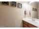 Bathroom with decorative signs on the walls, a mirror, and a sink with wood cabinets at 18226 W Stinson Dr, Surprise, AZ 85374